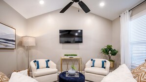 A modern living room with two sofas, a coffee table, a TV, and a ceiling fan. - The Paige, Cozy 1BR Studio by Velvet Ditch Villas (Oxford)