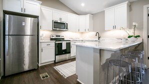 A modern kitchen with white cabinetry, stainless steel appliances, and a marble countertop. - The Paige, Cozy 1BR Studio by Velvet Ditch Villas (Oxford)