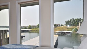 Un dormitorio con un amplio ventanal que da a un puerto deportivo y edificios.