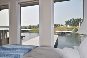 Una camera da letto con un'ampia finestra che si affaccia su un porto turistico e palazzi.