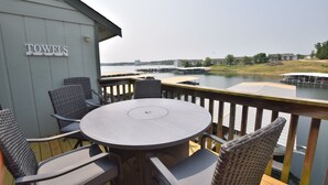 Una terraza con una mesa redonda y sillas, con vista a un cuerpo de agua con muelles y edificios a lo lejos.