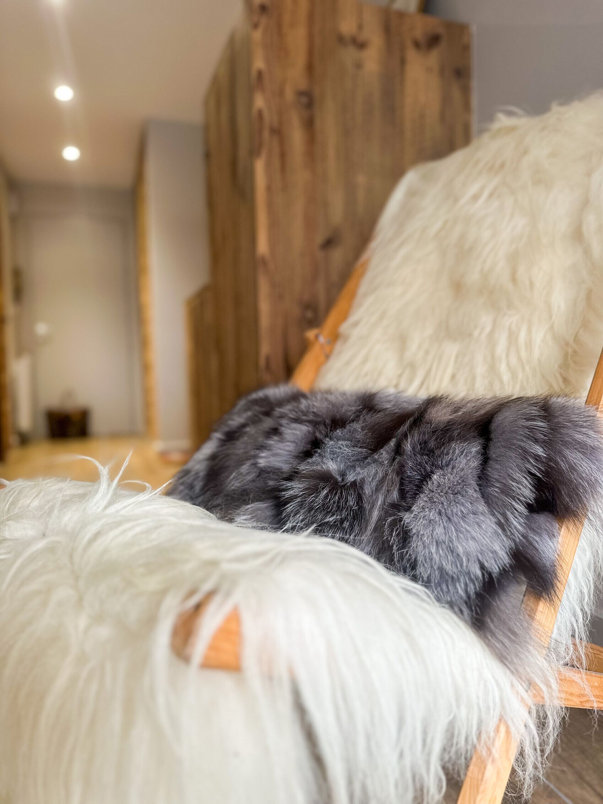 A wooden bed frame with a fluffy white and grey blanket.