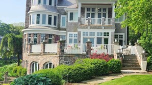 A multi-story house with a stone facade, multiple balconies, and a well-maintained garden. - Bayside Hideaway, Williams Bay, WI (Williams Bay)