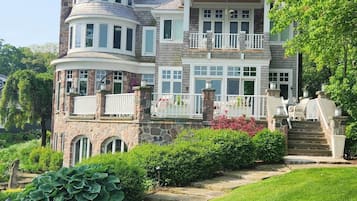 Une maison à plusieurs étages, dotée d’une façade en pierre, de nombreux balcons et d’un jardin bien entretenu.
