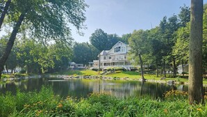 A large house with a pond in front, surrounded by greenery and trees. - Bayside Hideaway, Williams Bay, WI (Williams Bay)