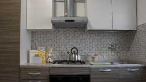 Cocina moderna con estufa a gas, hervidor y tostadora. Cuenta con alacenas de madera y salpicadero de azulejos.