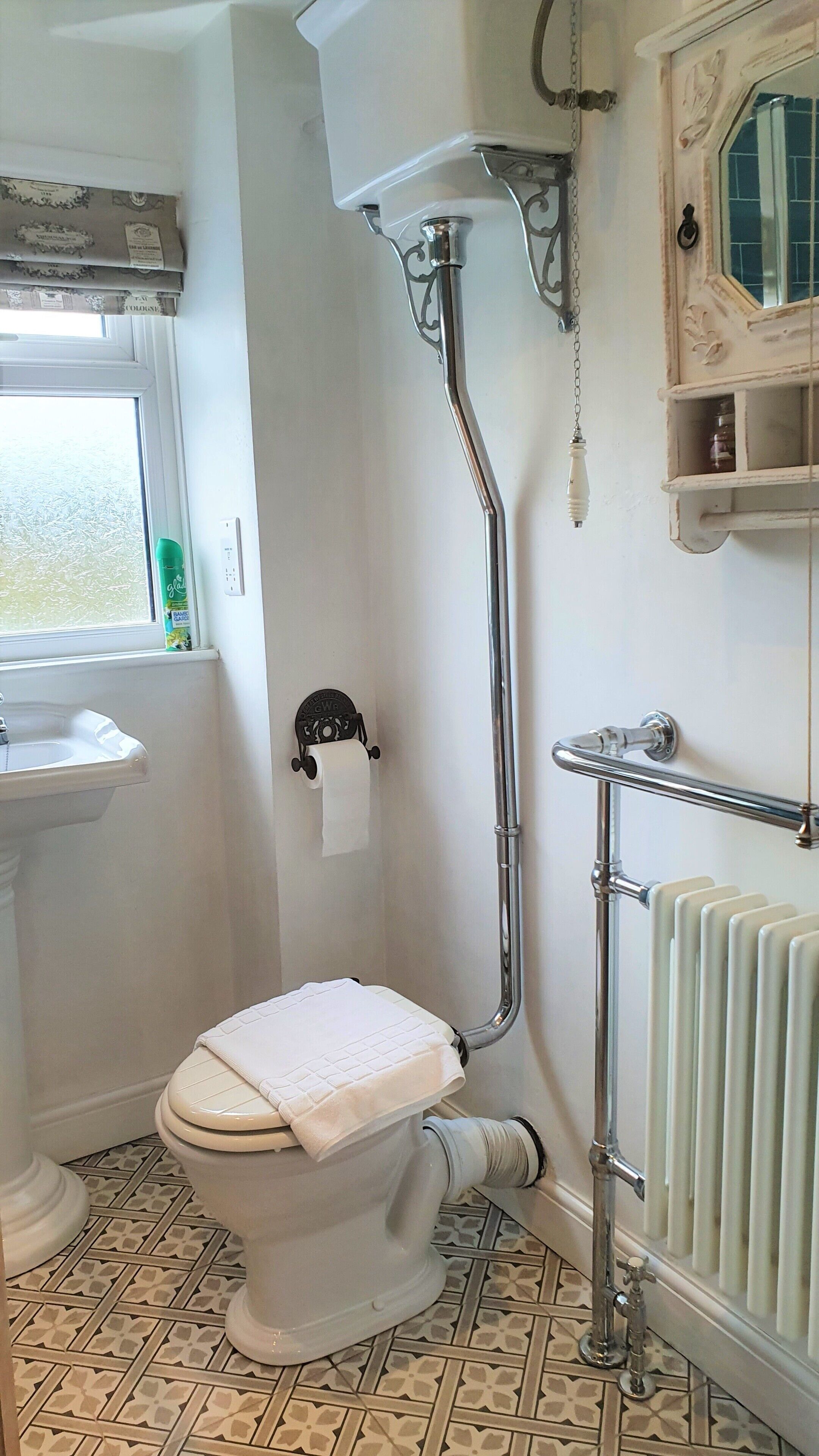 A bathroom with a toilet, a radiator, a sink, and a window.
