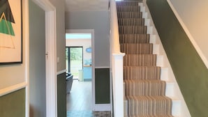 A staircase with carpeted steps and white handrails, leading to a door with a glass panel. - Large 5 Bedroom House Terrace Parking (Swindon)