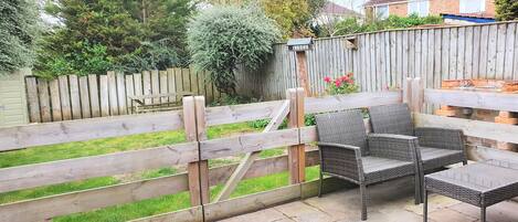 A patio area with wicker furniture and a wooden fence.