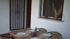 Een houten tafel voor vier personen, gedekt met borden, bestek en glazen.