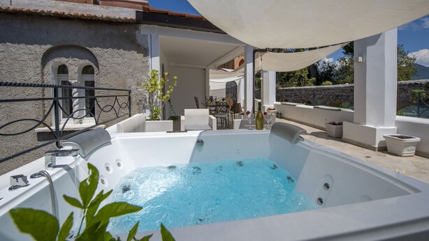 Área de piscina en la azotea con hidromasaje, mobiliario exterior y vistas del paisaje circundante.