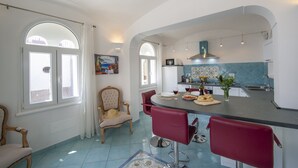 Una cocina amplia con comedor, que cuenta con una isla grande, taburetes de bar rojos y una silla clásica.