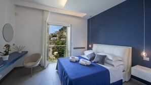 Een moderne slaapkamer met een bed, een stoel, een bureau en uitzicht op een heuvel.