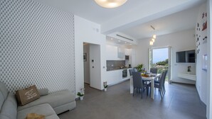 Een moderne woonruimte met een bank, eethoek, keuken en uitzicht op het groen.