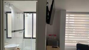 Um banheiro moderno com box de vidro, toucador de madeira e vaso sanitário.