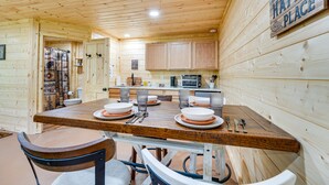 L’intérieur d’un chalet en bois, avec une table à manger dressée pour quatre personnes, des placards de cuisine et une pancarte indiquant : « Ce chalet est mon havre de paix. »