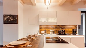 A modern kitchen with white cabinets, a wooden countertop, and a built-in coffee machine. - Ca' Luigia boutique apartment in Montorfano (Mergozzo)