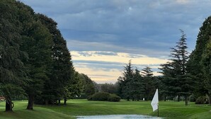 A golf course with a flag, trees, and a pond. - Ca' Luigia boutique apartment in Montorfano (Mergozzo)
