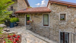 Una casa de piedra con techo de tejas, un balcón y una ventana pequeña.