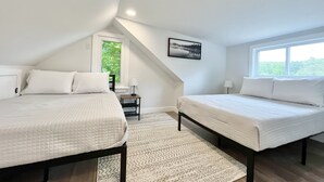 A bedroom with two beds, a window, a painting, and a view of greenery. - Lakefront Home on Lake Iroquois (Hinesburg)