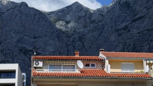 Un edificio con techo de tejas rojas, una antena parabólica y vistas a un paisaje montañoso.