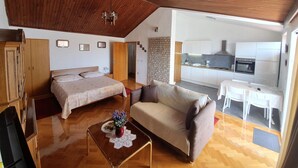 Un espacio habitable compacto con un entrepiso para dormir, un sofá, comedor y kitchenette.