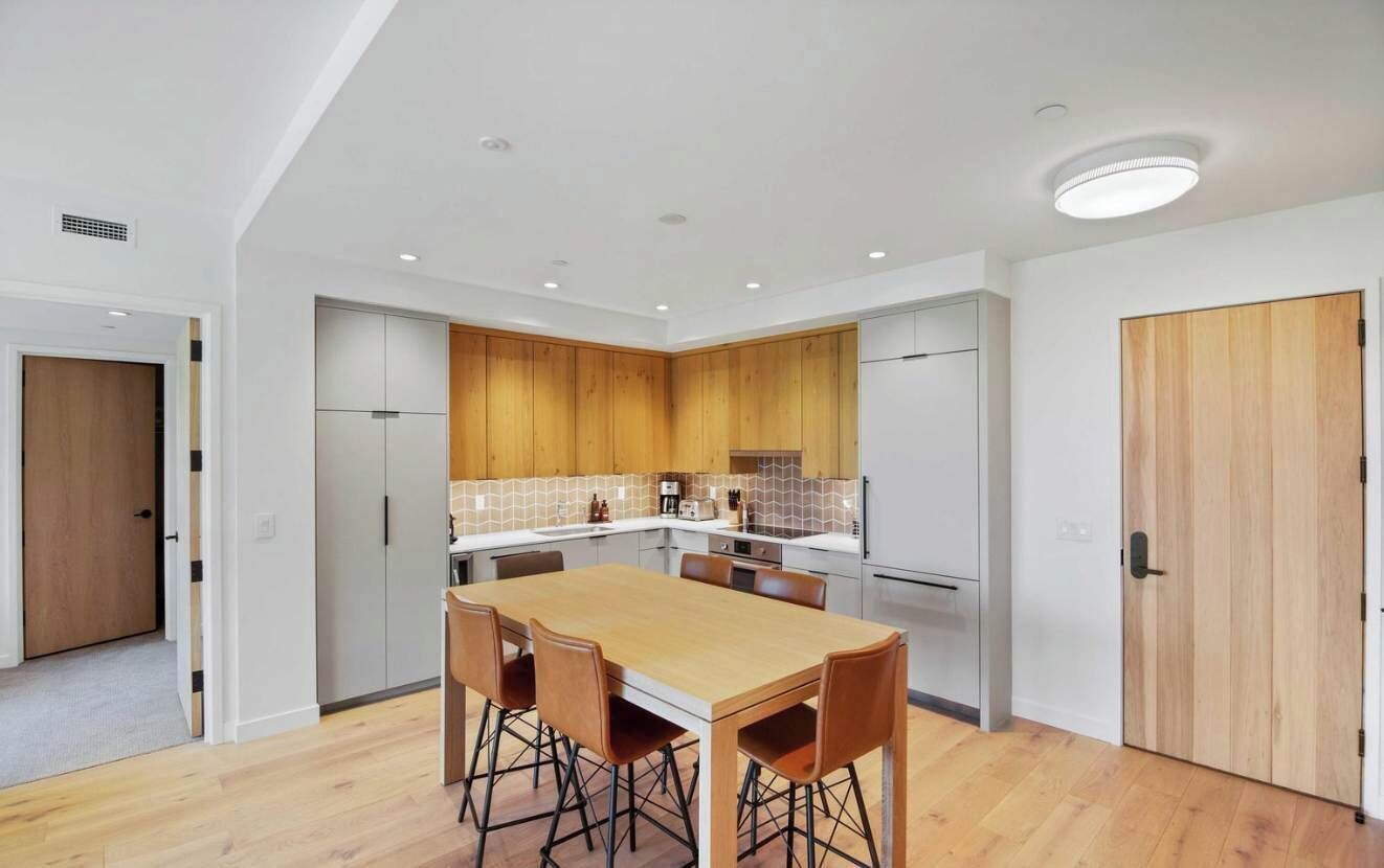 A modern kitchen with a central island, white cabinetry, and wooden accents.