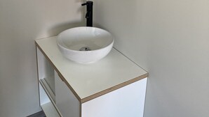 A bathroom with a white sink, black faucet, and a wooden-framed mirror. - Maison Climatisée Avec Piscine Entre Montalivet et Soulac (Grayan-et-l'Hôpital)