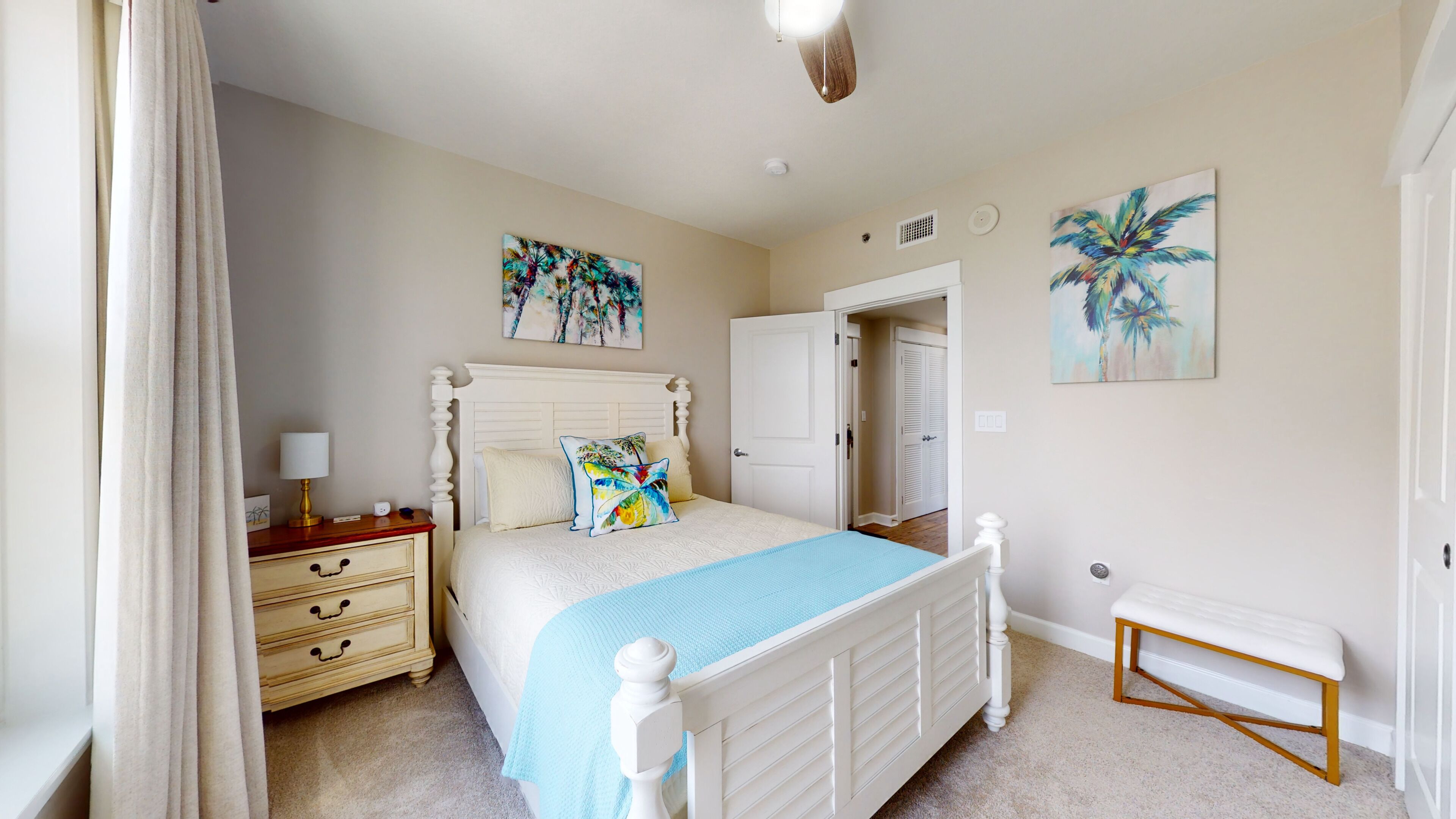 A bedroom with a bed, nightstand, dresser, and a bench. There are two doors, one leading to a closet and another to a bathroom.
