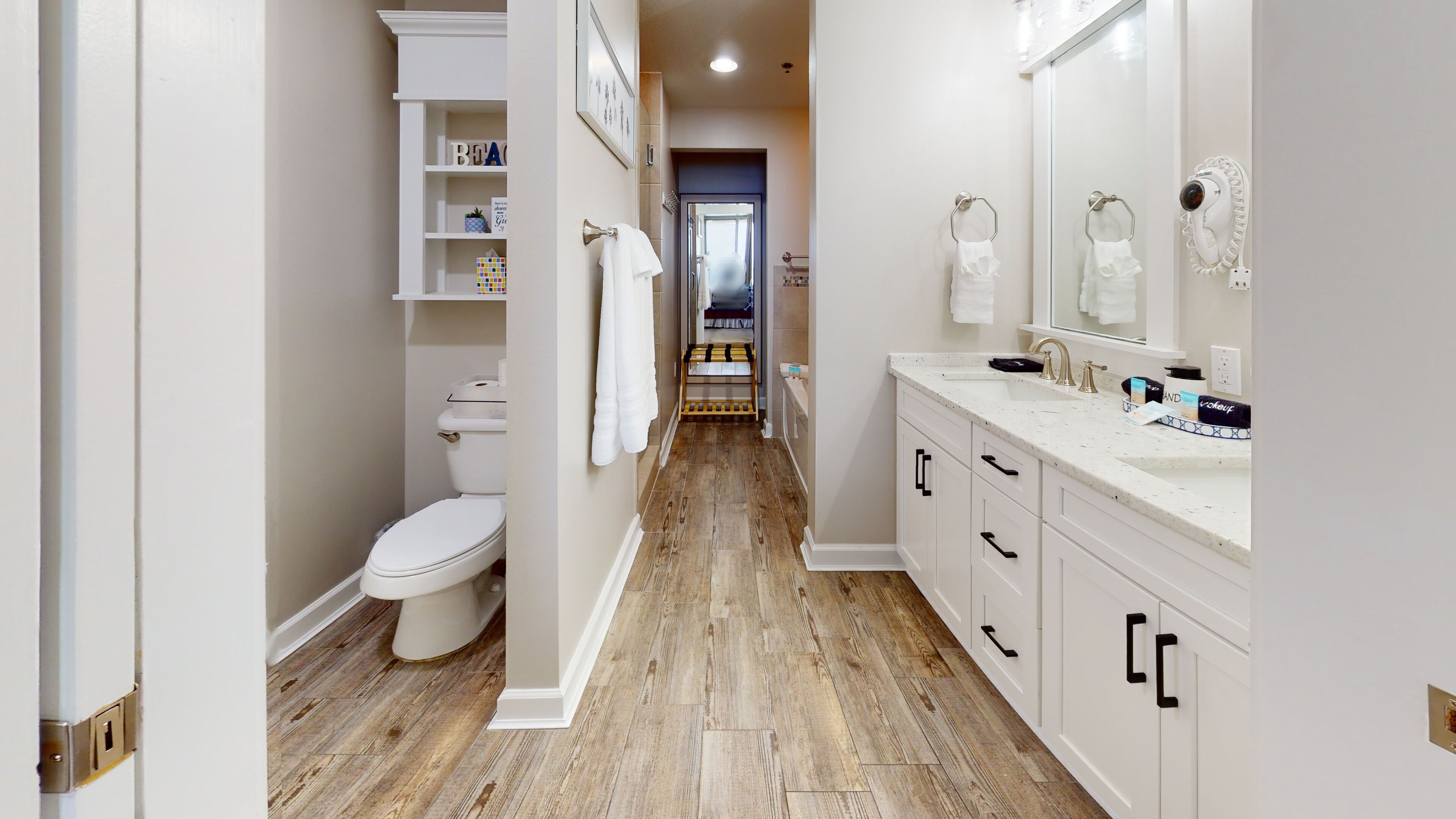 A modern bathroom with a wooden floor, white fixtures, and a visible toilet.
