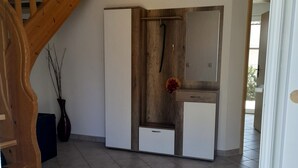 A modern interior with a wooden staircase, a white wardrobe, and a decorative vase.