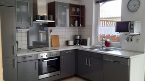 A modern kitchen with grey cabinets, stainless steel appliances, and a built-in oven.