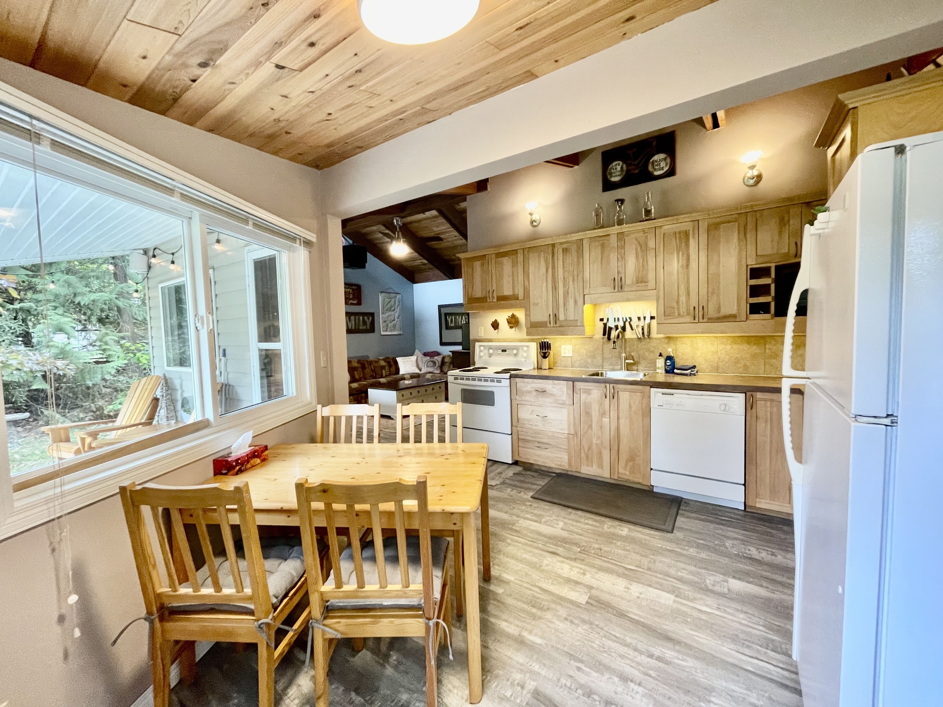 Une cuisine moderne avec des meubles en bois, une table à manger avec des chaises et une grande fenêtre.