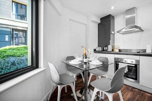 Eine moderne Küche mit Essbereich, einem großen Fenster und Blick ins Grüne.