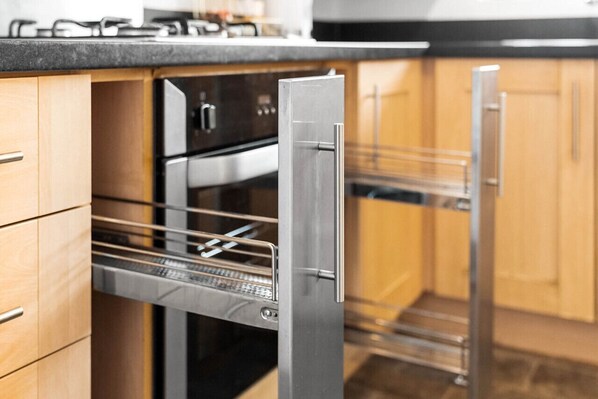 Une cuisine moderne dotée d’appareils électroménagers en acier inoxydable, de meubles en bois et d’un four encastré.