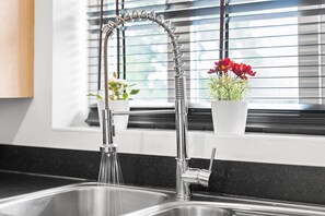 A modern kitchen with a stainless steel sink, a flexible faucet, and a window with blinds. - 2 Bedroom House - Parking - Garden - Oldbury (Oldbury)