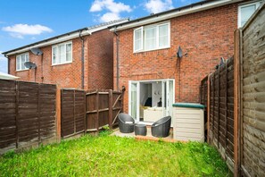 A brick house with a wooden fence, a small patio with outdoor furniture, and satellite dishes on the roof. - 2 Bedroom House - Parking - Garden - Oldbury (Oldbury)