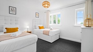 Une chambre d’hôtel moderne avec deux lits, une fenêtre avec des rideaux, une table de chevet avec une lampe et un panier décoratif.