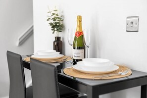 A dining table set with plates, cutlery, and a bottle of vintage Codorniu champagne. - 2 Bedroom House - Parking - Garden - Oldbury (Oldbury)