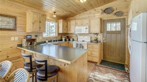 Una cabaña de madera con cocina que cuenta con una isla grande, taburetes de bar y un refrigerador.