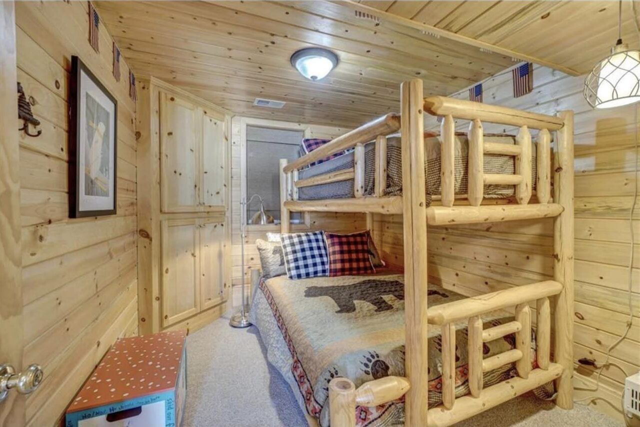 A cabin with a bunk bed, wooden walls, a framed picture, and a small table.