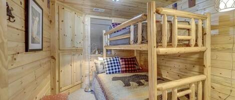 A cabin with a bunk bed, wooden walls, a framed picture, and a small table.