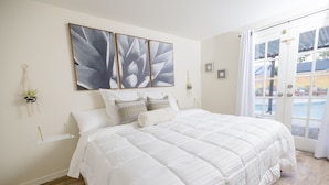 A bedroom with a large bed, a door leading to a pool area, and wall-mounted decor. - ༄The Agave Ranch༄ FREE Pool Heating & Arcade Room! (Phoenix)