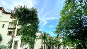 A residential area with a paved road, buildings with balconies, and greenery.