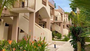 A pathway leading to a building with multiple balconies, surrounded by lush greenery and flowering plants. - EndlessSummer Beach Escape (Playas Del Coco)