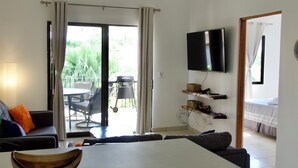 A dining area with a table and chairs, a ceiling fan, a television mounted on the wall, and a sliding glass door leading to an outdoor patio with a table and chairs.