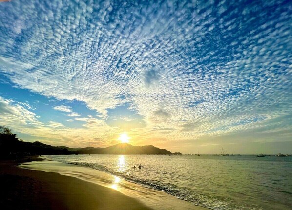 Une plage avec un ciel dégagé, où l’on peut admirer le soleil se coucher ou se lever sur l’eau.