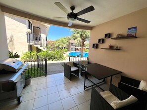 Un espace patio équipé d’un barbecue, de sièges et offrant une vue sur la piscine.