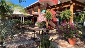 An outdoor patio area with tables and chairs, surrounded by potted plants and a mural. - Sea Bottom Ground Condo (Playas Del Coco)