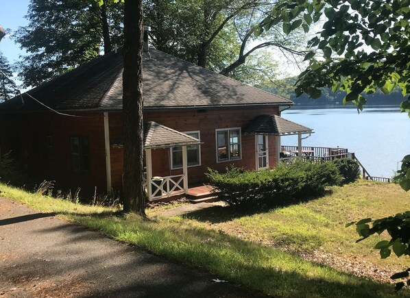 A small cabin with a porch and a view of a lake.